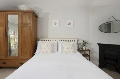 a bedroom with a white bed and a wooden cabinet at Trevethen Cottage - Free Parking and WiFi - Close to Beach - Pets Welcome in Crantock