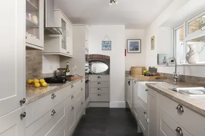 a kitchen with white cabinets and a counter top at Trevethen Cottage - Free Parking and WiFi - Close to Beach - Pets Welcome in Crantock