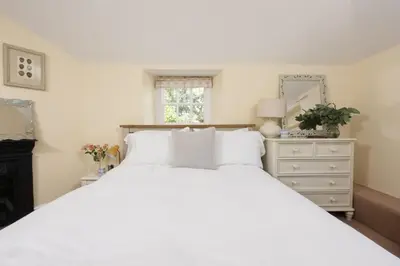 a bedroom with a large white bed and a dresser at Trevethen Cottage - Free Parking and WiFi - Close to Beach - Pets Welcome in Crantock