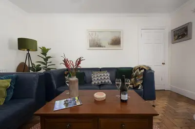 a living room with a blue couch and a coffee table at Trevethen Cottage - Free Parking and WiFi - Close to Beach - Pets Welcome in Crantock
