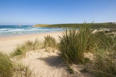 a sandy beach with some grass and the ocean at Trevethen Cottage - Free Parking and WiFi - Close to Beach - Pets Welcome in Crantock