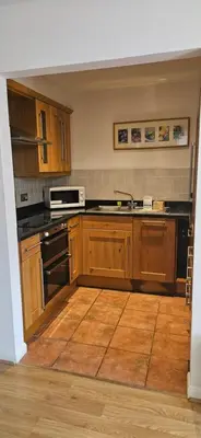 a kitchen with wooden cabinets and black appliances at Family and dog-friendly holiday home - 134 Hengar Manor in Saint Tudy