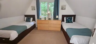 a bedroom with two beds and a dresser and a window at Family and dog-friendly holiday home - 134 Hengar Manor in Saint Tudy