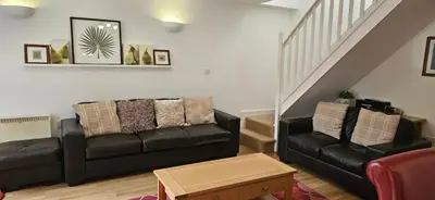 a living room with a black couch and a staircase at Family and dog-friendly holiday home - 134 Hengar Manor in Saint Tudy