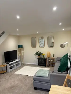a living room with a couch and a tv and mirrors at Cute Cornish Cottage in Saint Germans