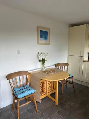 a dining room table with two chairs and a vase of flowers at The Beach Hut in Perranporth