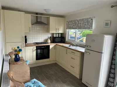 a kitchen with a white refrigerator and a sink at The Beach Hut in Perranporth
