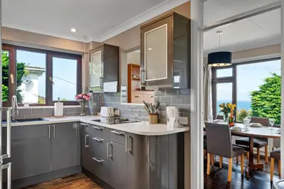a kitchen with gray cabinets and a dining room with a table at Finest Retreats - Michel in Carbis Bay