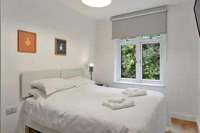 a bedroom with a white bed with two stuffed animals on it at Finest Retreats - Three Quarter Cottage in Bodinnick
