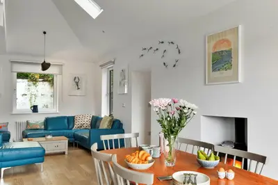 a living room with a table and a blue couch at Finest Retreats - Three Quarter Cottage in Bodinnick