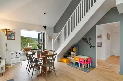 a living room with a table and chairs and a staircase at Finest Retreats - Three Quarter Cottage in Bodinnick