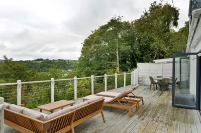 a deck with benches and tables on a house at Finest Retreats - Three Quarter Cottage in Bodinnick