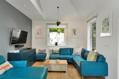 a living room with blue couches and a tv at Finest Retreats - Three Quarter Cottage in Bodinnick