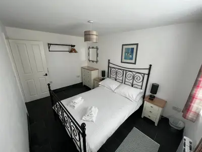 a bedroom with a bed with a black frame at Hollowell House Holiday Apartment in Boscastle