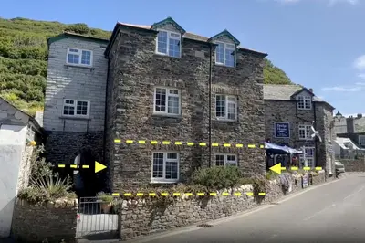 a stone building with two windows and two arrows at Hollowell House Holiday Apartment in Boscastle