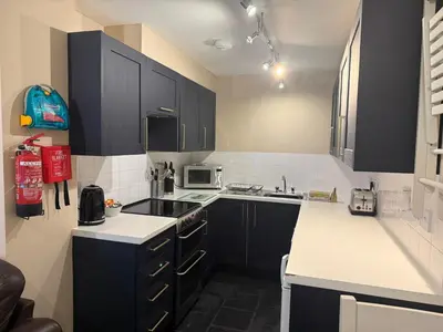a kitchen with black cabinets and white counter tops at Hollowell House Holiday Apartment in Boscastle