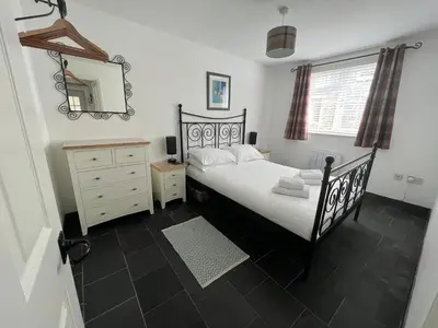 a bedroom with a black bed and a mirror at Hollowell House Holiday Apartment in Boscastle