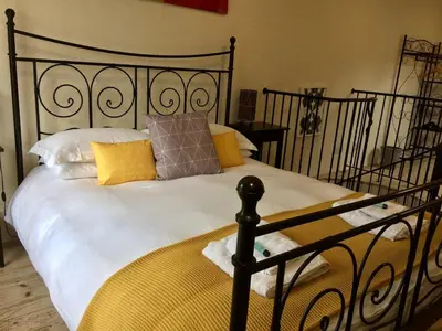 a bedroom with a large bed with yellow pillows at Coach House Studio, quiet, rural, pet friendly, Probus in Probus