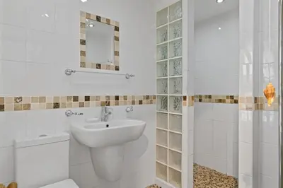 a white bathroom with a sink and a toilet at Cosy Fisherman's Cottage Seconds from Waterfront in St Ives