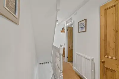a hallway with white walls and a wooden door at Cosy Fisherman's Cottage Seconds from Waterfront in St Ives