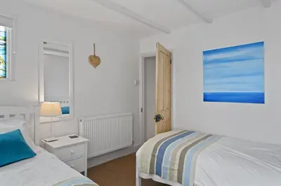 a white bedroom with a bed and a window at Cosy Fisherman's Cottage Seconds from Waterfront in St Ives