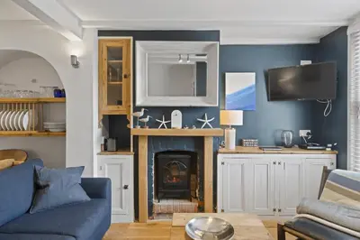 a living room with a fireplace and blue walls at Cosy Fisherman's Cottage Seconds from Waterfront in St Ives