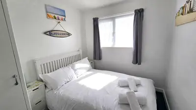 a bedroom with a bed with two towels on it at Chalet 150, Perran Sands in Perranporth