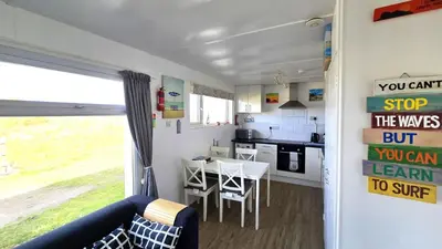 a kitchen with a table and a dining room at Chalet 150, Perran Sands in Perranporth