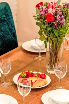 a table with plates of food and a vase with flowers at Holiday Home Tregony House 1 Bedroom by Interhome in Mevagissey