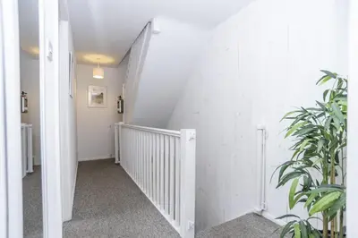 a hallway with white walls and a staircase with a plant at St Ives Holiday Cottage with Parking – Coastal Retreat in St Ives