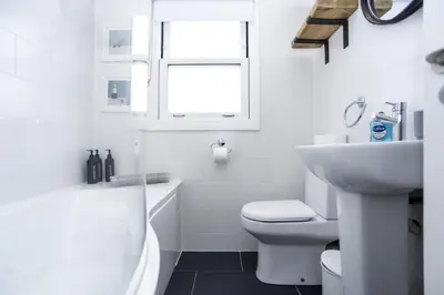 a white bathroom with a toilet and a sink at St Ives Holiday Cottage with Parking – Coastal Retreat in St Ives
