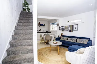a living room with a staircase and a blue couch at St Ives Holiday Cottage with Parking – Coastal Retreat in St Ives