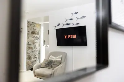 a living room with a chair and a tv at St Ives Holiday Cottage with Parking – Coastal Retreat in St Ives
