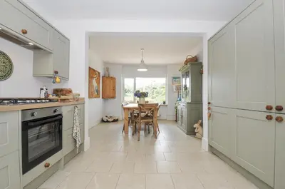 a kitchen with white cabinets and a table at Mayhurst in Looe