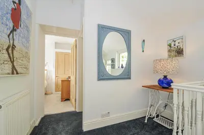 a hallway with a mirror and a table at Mayhurst in Looe