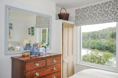 a bedroom with a dresser and a large window at Mayhurst in Looe