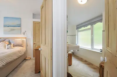 a bedroom with a bed and a sink and a window at Mayhurst in Looe
