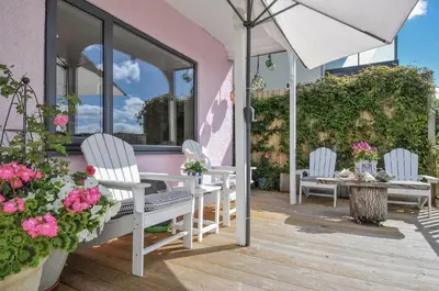 a patio with two chairs and a table and an umbrella at Mayhurst in Looe