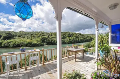 a porch with a table and chairs and a view of a river at Mayhurst in Looe