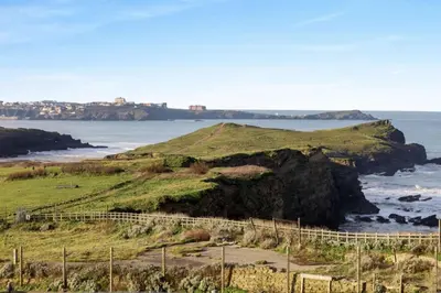 a view of the ocean from a hill with a fence at 1 Bed in Newquay oc-c33290 in Saint Columb Major