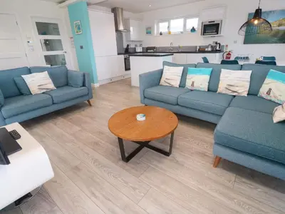 a living room with blue couches and a coffee table at Lodge 83, Gwel an Mor in Redruth
