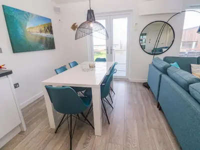 a dining room with a table and chairs and a couch at Lodge 83, Gwel an Mor in Redruth
