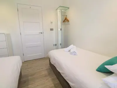 a small bedroom with two beds and a door at Lodge 83, Gwel an Mor in Redruth