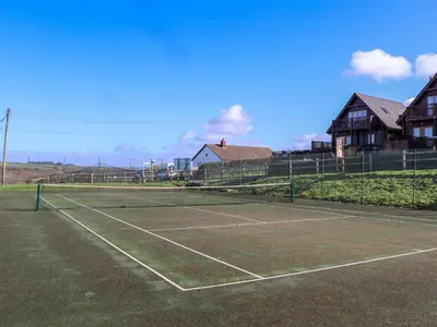a tennis court with a tennis racket on it at Lodge 83, Gwel an Mor in Redruth