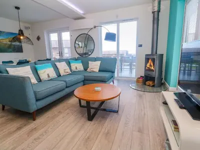 a living room with a blue couch and a fireplace at Lodge 83, Gwel an Mor in Redruth