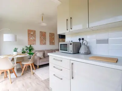 a kitchen and living room with a microwave and a table at Cozy Retreat in Padstow