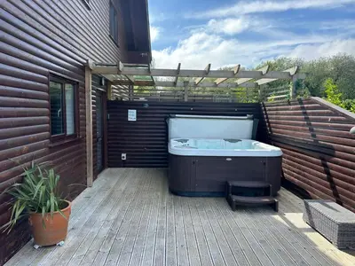 a hot tub sitting on a deck next to a building at Redwood at Retallack Resort in Saint Columb Major