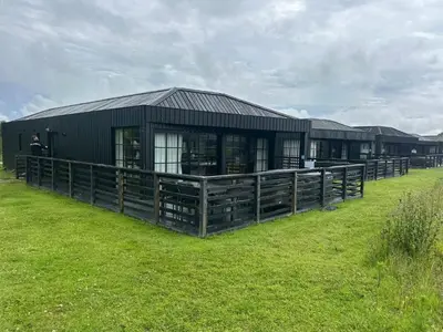 a black building in a field with a grass yard at Barn 21 at Retallack Resort in Saint Columb Major