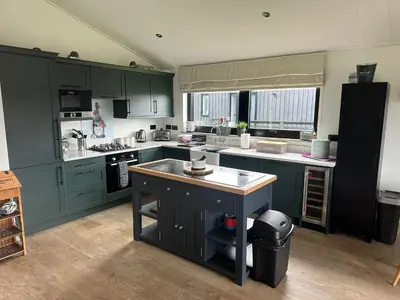 a kitchen with green cabinets and a island in it at Barn 21 at Retallack Resort in Saint Columb Major