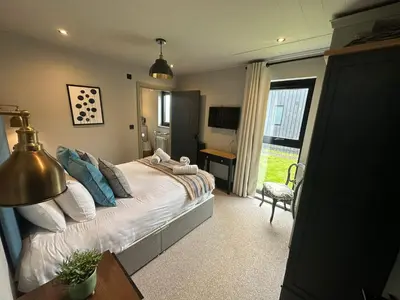 a bedroom with a bed and a desk and a window at Barn 21 at Retallack Resort in Saint Columb Major